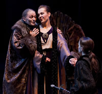Claudius reassures Gertrude, as Hamlet looks on